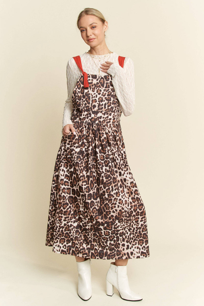 Woman wearing a leopard print dress with red straps against a beige background