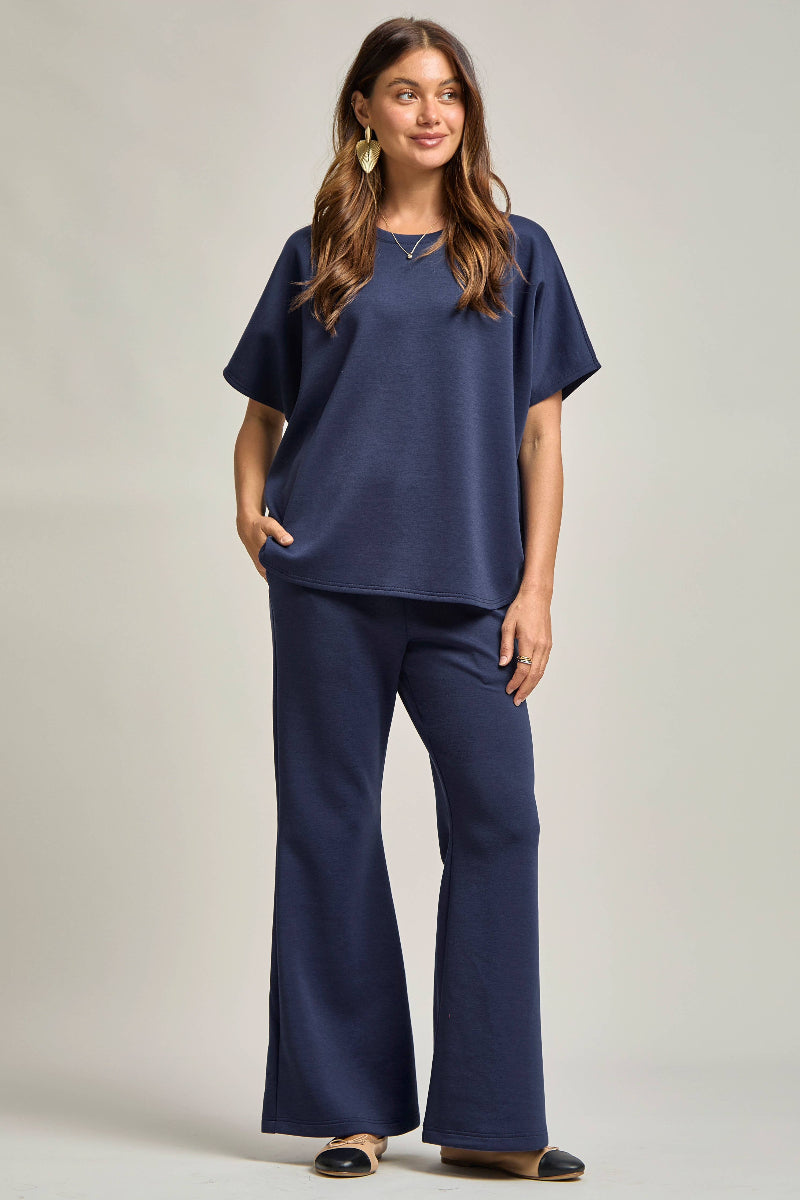 Woman wearing a navy blue outfit with wide-leg pants on a plain background