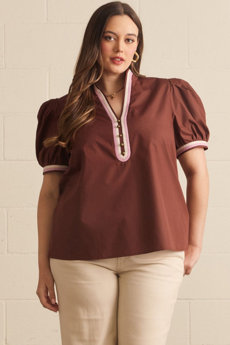 Plus size woman wearing a chocolate brown short puff sleeve top with contrast V-neckline binding and contrast cuffs, styled with cream trousers — Mirror on Main
