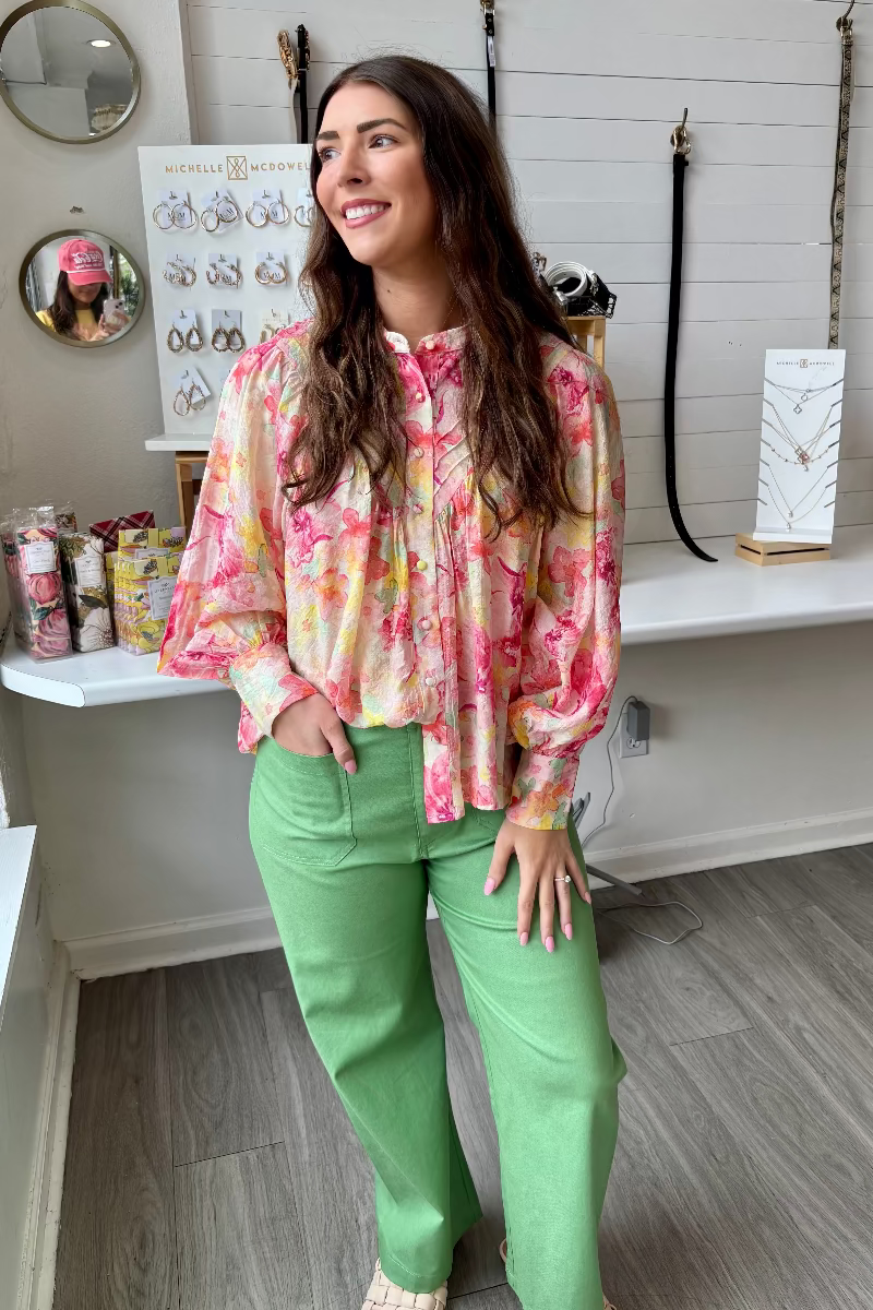 Woman wearing a colorful blouse and green pants in Mirror On Main