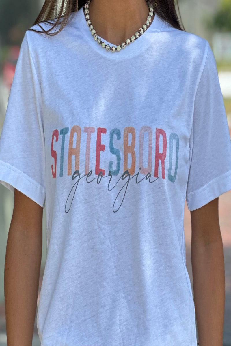 Person wearing a white t-shirt with 'Statesboro Georgia' printed on it, standing outdoors.