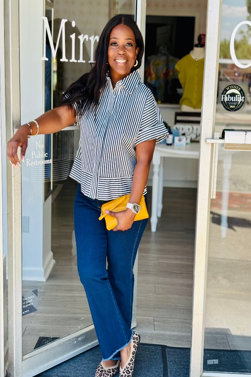 Woman wearing a navy and white striped shirt with dark denim jeans in front of Mirror On Main