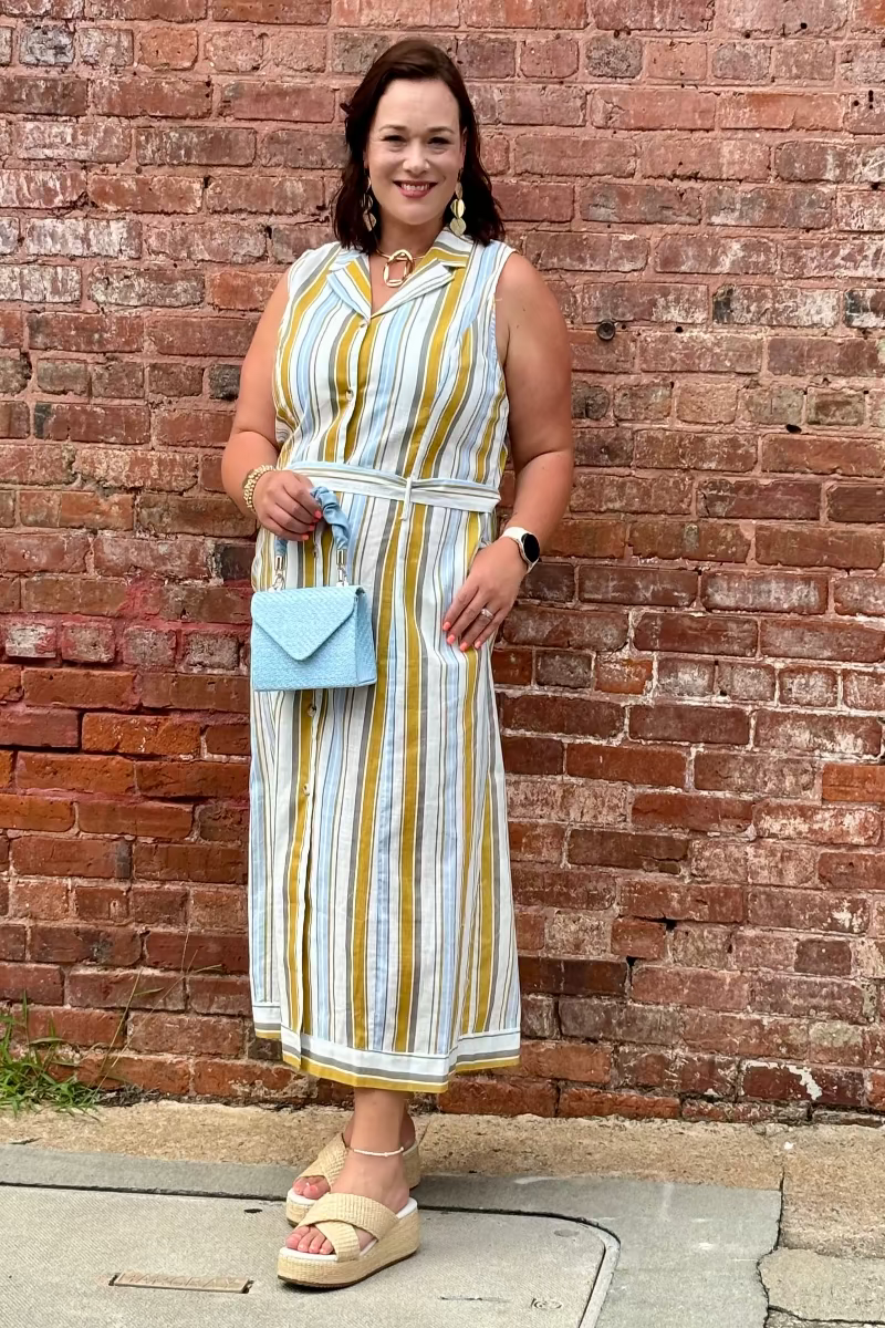Woman in a striped dress standing against a brick wall Mirror On Main