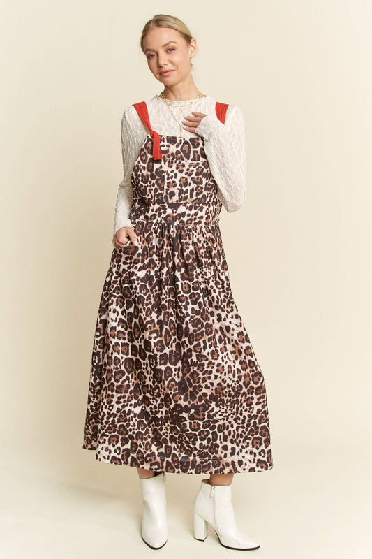Woman wearing a leopard print dress with red straps against a beige background