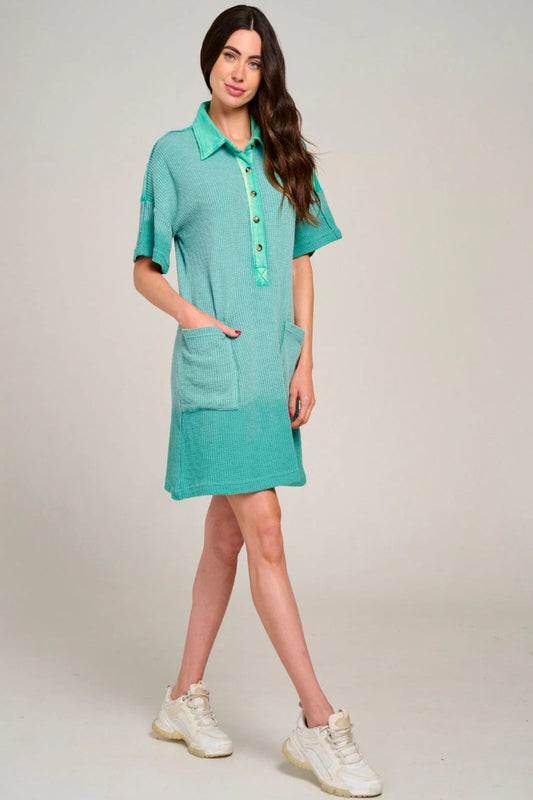 Woman wearing a teal dress with a plain background