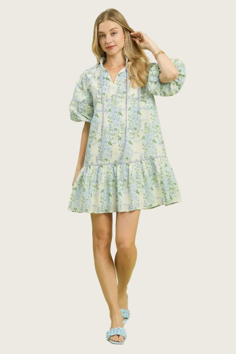 Blue floral and botanical print 100% cotton babydoll mini dress with tie-up neckline, twisted cord accents, puff sleeves with ruffle trim, and tiered ruffle hem — Mirror on Main