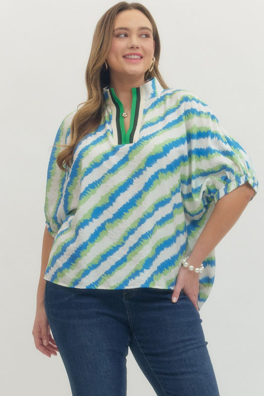 Plus size woman wearing a blue green ivory wave print dolman sleeve top with contrast trim split neckline, styled with dark denim — Mirror on Main