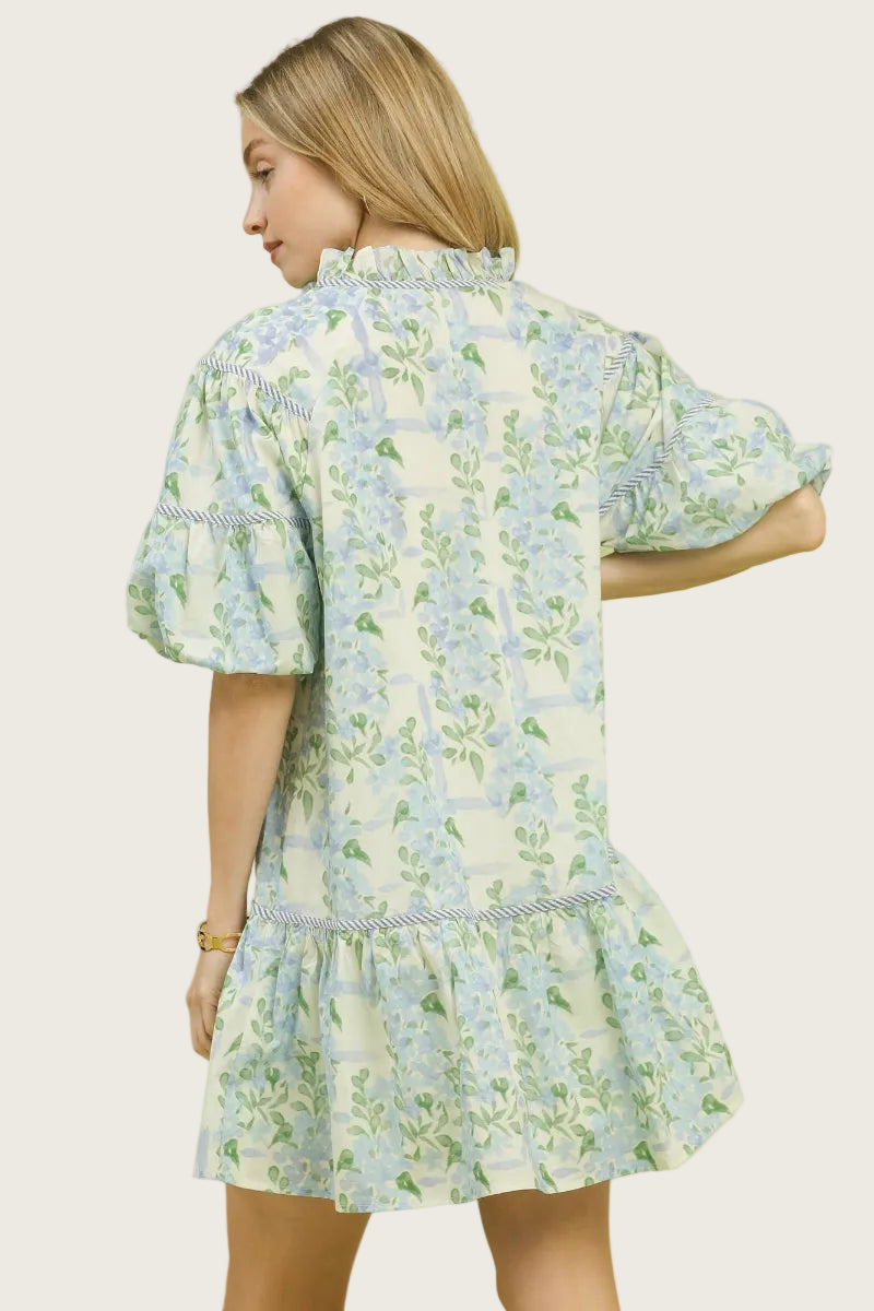 Blue floral and botanical print 100% cotton babydoll mini dress with tie-up neckline, twisted cord accents, puff sleeves with ruffle trim, and tiered ruffle hem — Mirror on Main