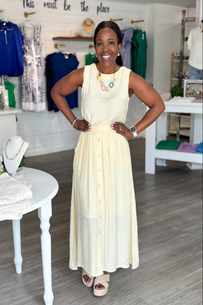 Woman in a white dress standing in a store with clothing and jewelry on display at Mirror On Main