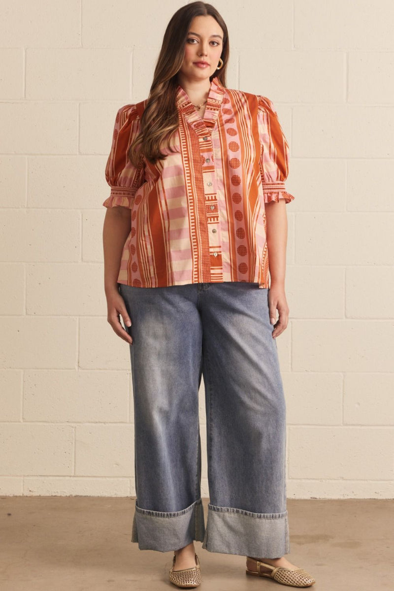 Plus size woman wearing a cinnamon mixed print puff sleeve top with ruffle neckline and smocked cuffs, styled with wide-leg denim — Mirror on Main