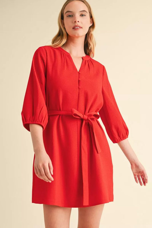 Close-up of red waffle textured mini dress showing self-tie belt, V-neck and three-quarter sleeves – Mirror On Main.