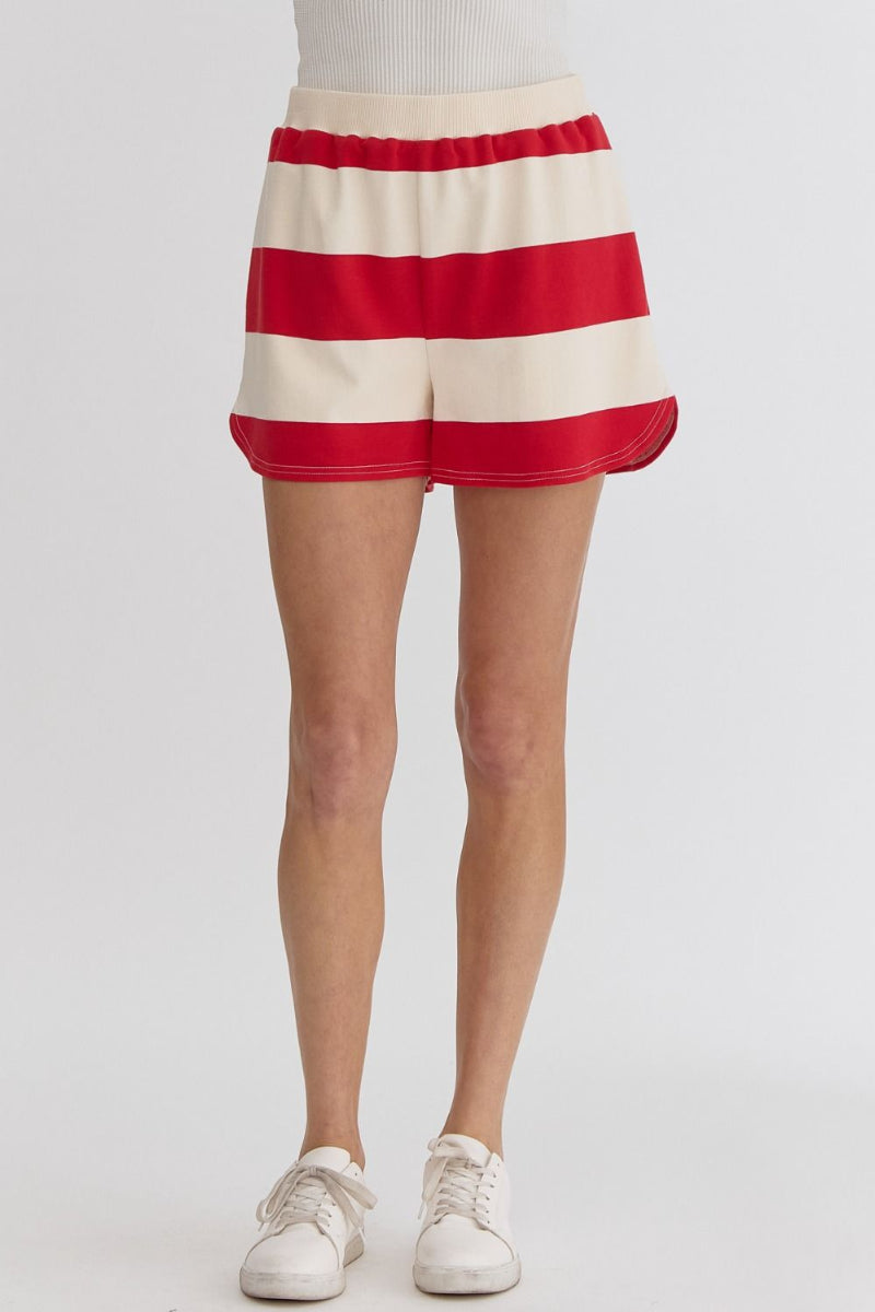 Red and cream striped cotton shorts with an elastic waistband and side pockets, styled casually with sneakers.