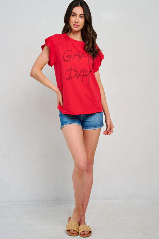Woman wearing a red 'Game Day' t-shirt and denim shorts on a white background