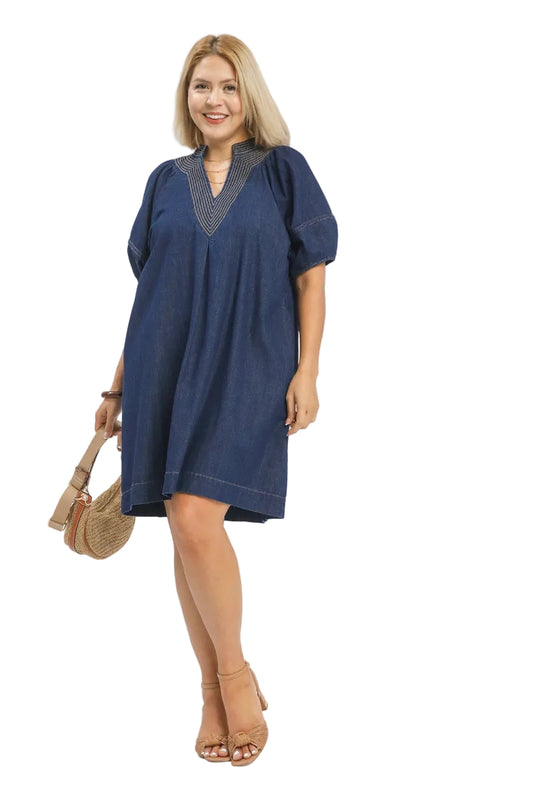 Plus size woman wearing a denim A-line dress with puff sleeves, deep V-neck, and contrast stitching — Mirror on Main