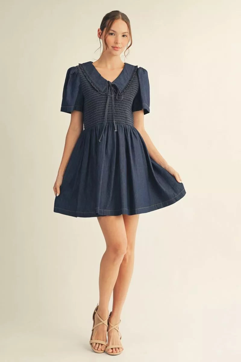 Full-length model view of denim blue skater mini dress with Peter Pan collar, short puff sleeves and flared skirt at Mirror On Main