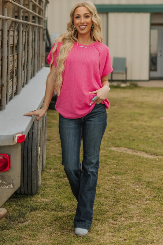Woman in a pink shirt and blue jeans standing next to a truck