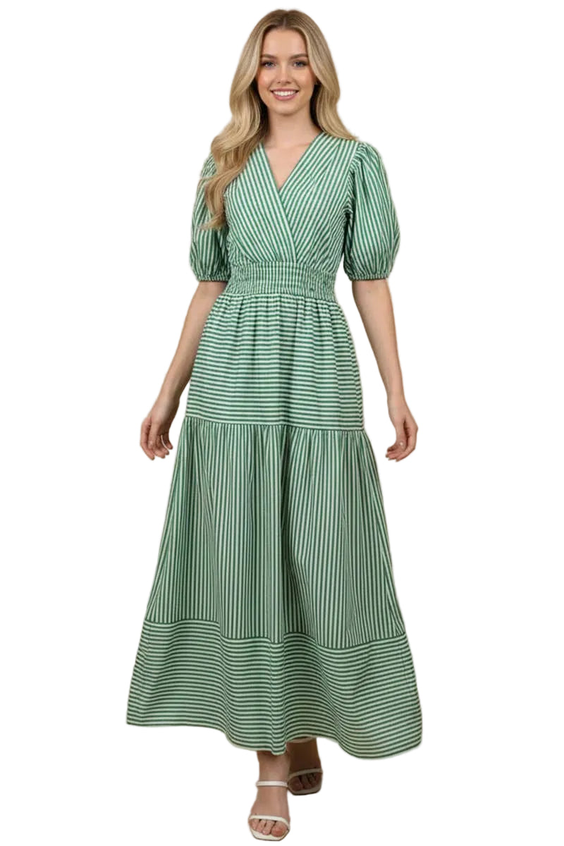 Woman wearing a green and white striped maxi dress with a surplice V-neckline, short balloon sleeves, wide elastic waist, tiered full skirt, and side pockets