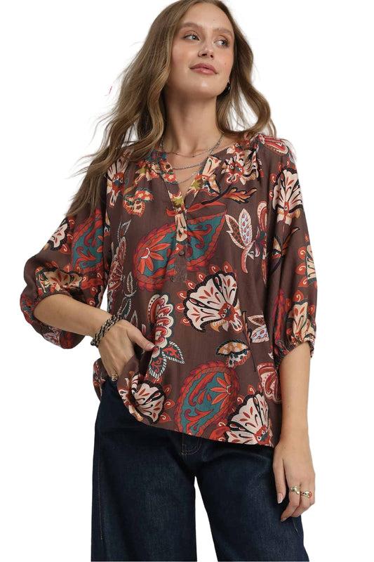 Woman wearing a patterned blouse with 'UMEE Exclusive' branding on a white background