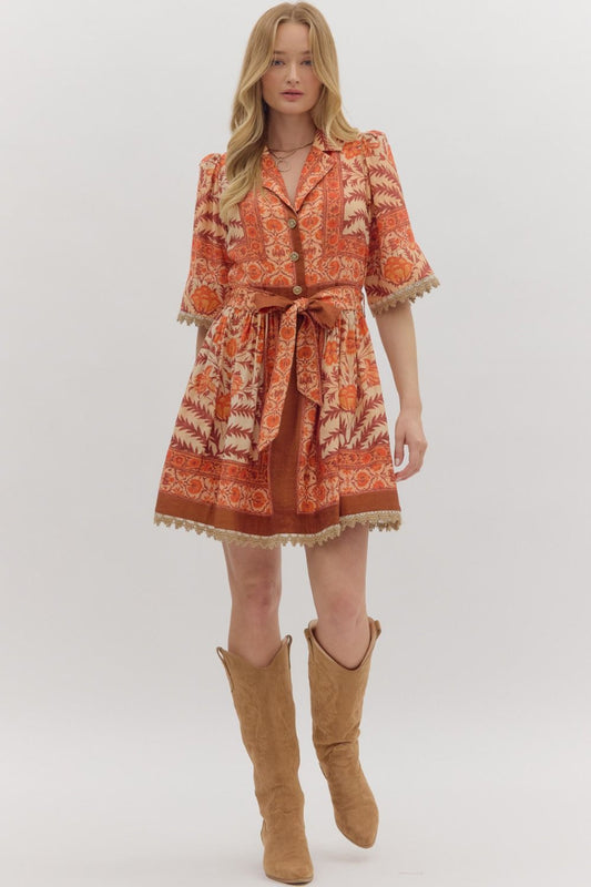 Woman wearing a patterned dress with a belt and tan knee-high boots on a white background