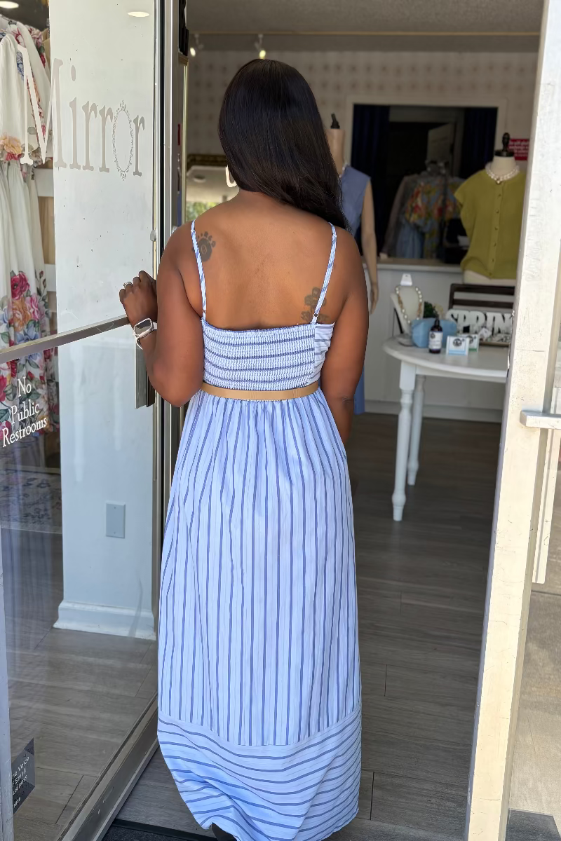 Woman in a blue striped dress standing in front of a mirror.