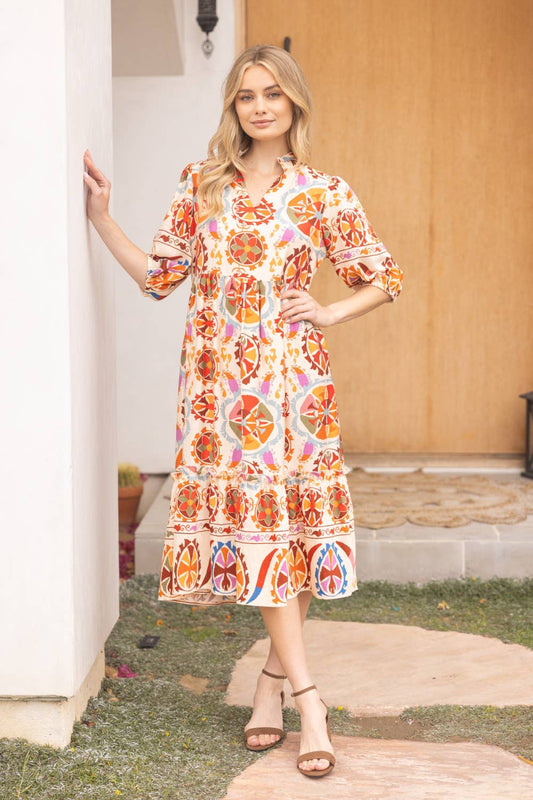 Woman wearing a colorful patterned dress standing outdoors.