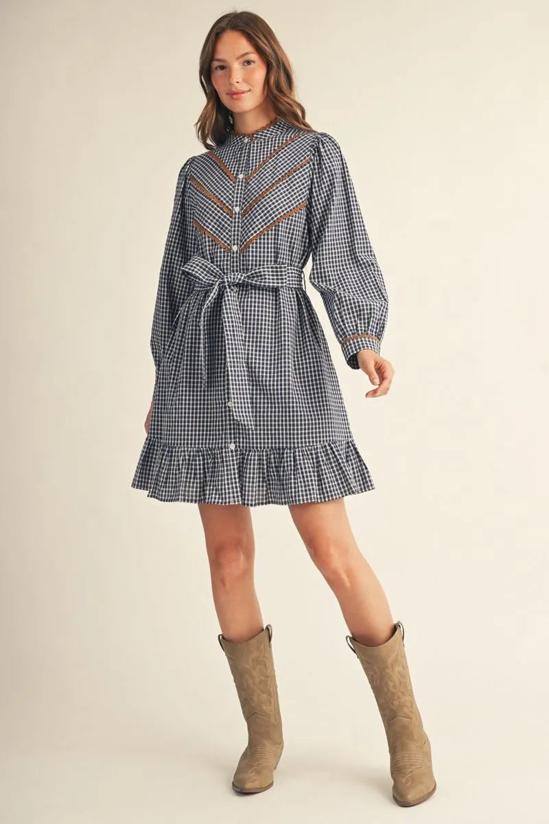 Woman wearing a navy gingham plaid long sleeve button-down shirt dress with scallop trim, self-tie waist, and ruffled hem, styled with tan cowboy boots — Mirror on Main