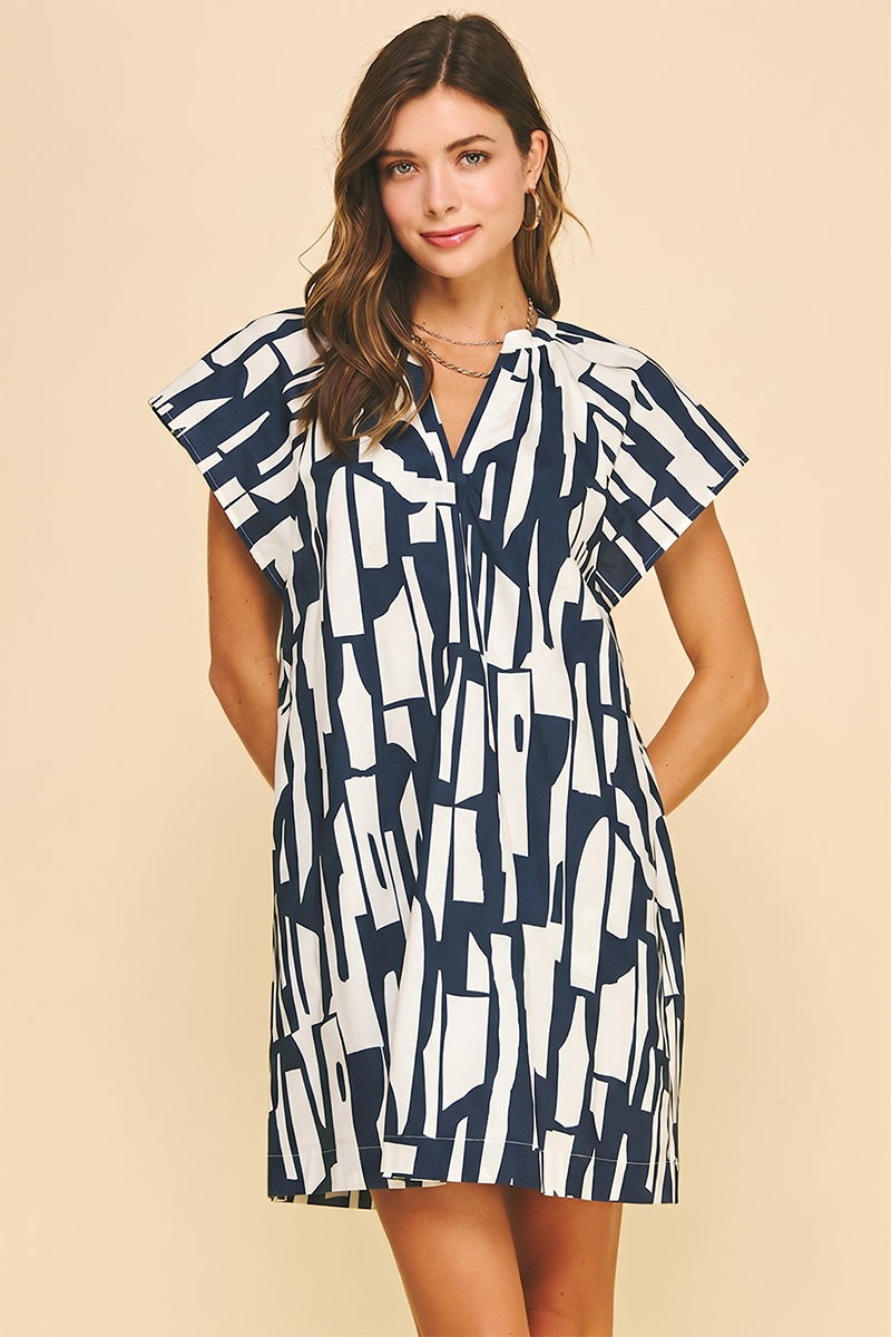 Woman wearing a navy and ivory abstract print cotton mini dress with cap sleeves, open V-neckline, and back neck shirring — Mirror on Main