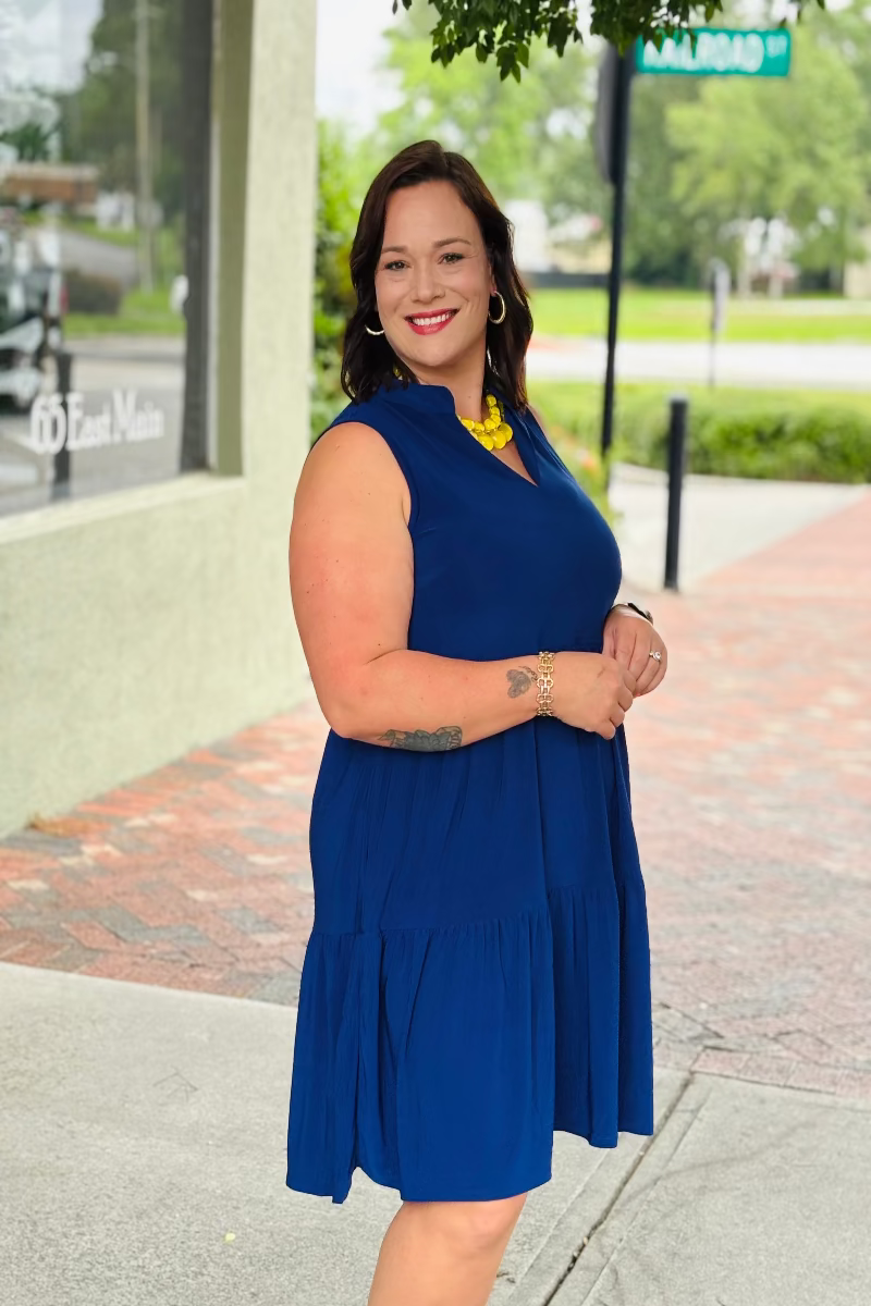Woman in a blue dress standing on a sidewalk with a street sign in the background at Mirror On Main