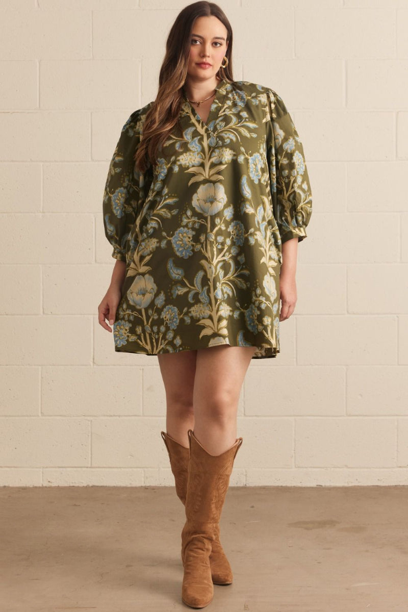 Woman wearing an olive green botanical floral puff sleeve mini dress with V-neck collar, styled with tan cowboy boots — Mirror on Main