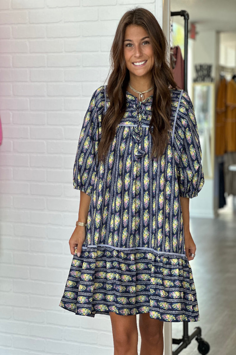 Woman wearing a blue dress with yellow patterns in an indoor setting