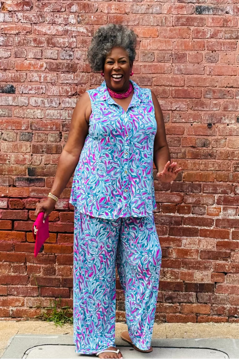 Woman in a colorful outfit standing against a brick wall Mirror On Main 