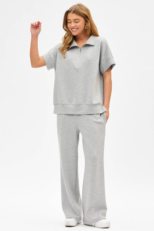 Woman wearing a gray outfit with a top and pants on a white background