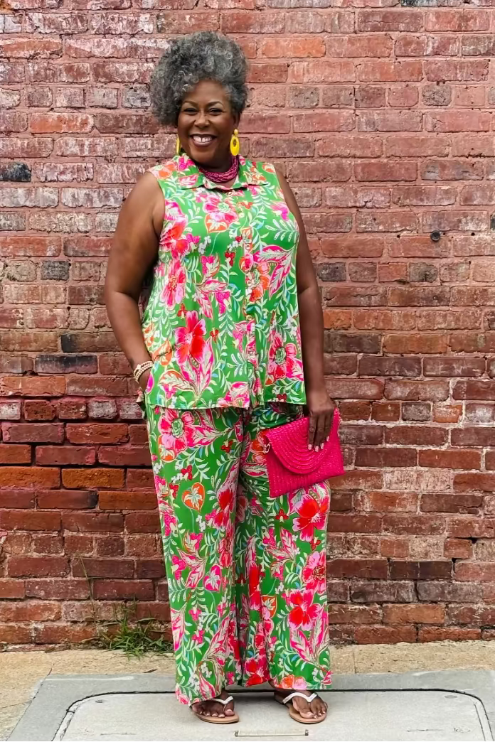 Woman in a colorful floral outfit standing against a brick wall at Mirror On Main.