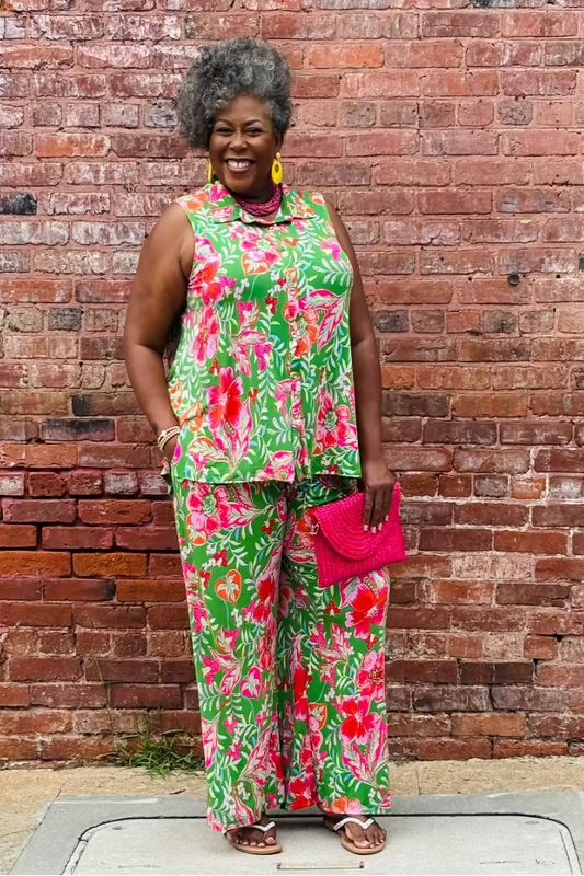 Woman in a colorful floral outfit standing against a brick wall at Mirror On Main.