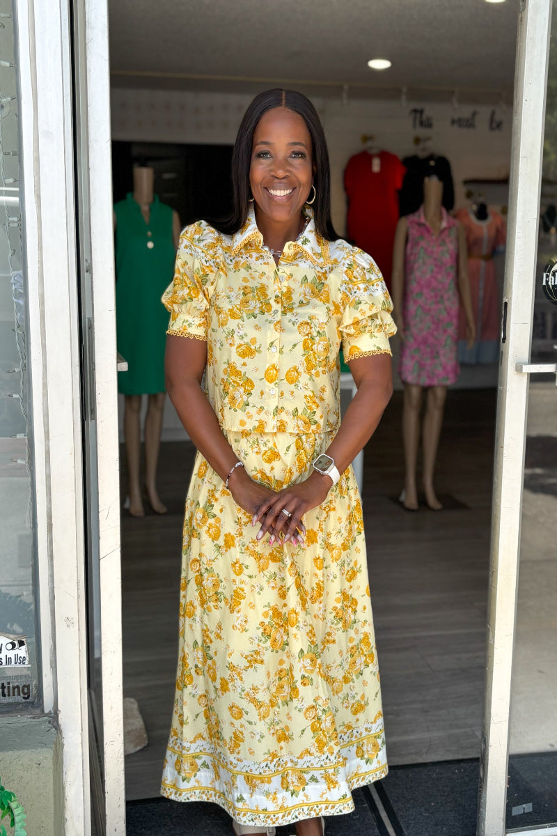 Woman wearing a yellow floral dress standing in a store Mirror On Main