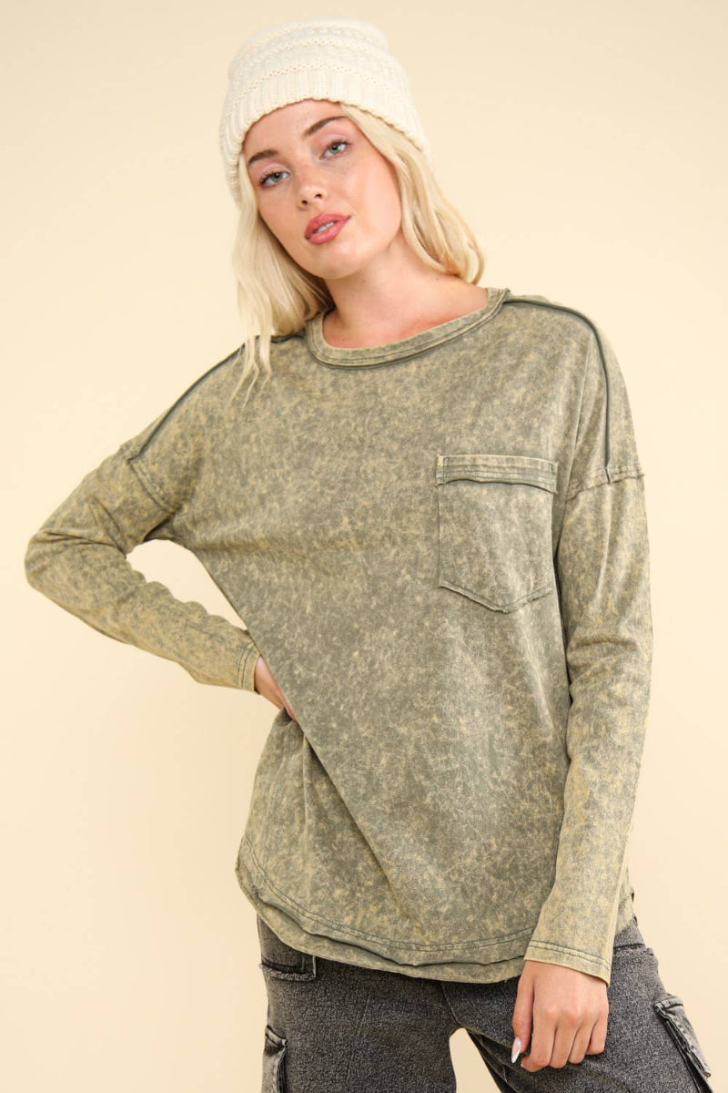 A female model wearing a long-sleeved, casual mineral washed top in sage color with a crew neckline, featuring a front patch pocket.