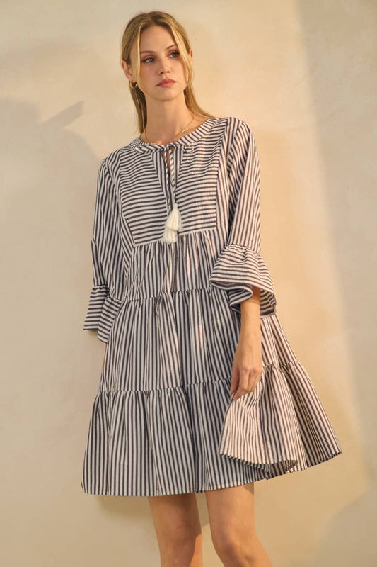 Woman wearing a black and white striped dress against a neutral background