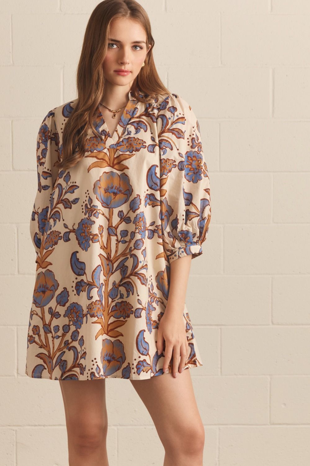 Woman wearing an ecru floral puff sleeve mini dress with blue and caramel blooms and a V-neck collar – Mirror On Main